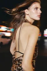 Top de cuello halter con escote fluido y espalda descubierta con tiras a contraste, cubierto de lentejuelas doradas.