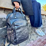 Mochila de cuero color marrón claro con múltiples bolsillos y cierres.