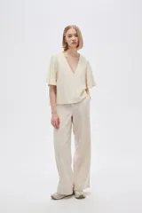 Blusa color crema de viscosa con escote en V y mangas cortas acampanadas.