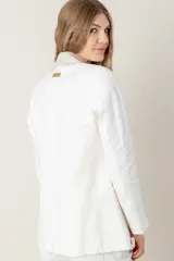 Blazer de lino color blanco con solapas y cuello en color beige, corte entallado, botón de nácar, tajo en la espalda y bolsillos laterales.