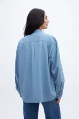 Camisa celeste de denim de algodón, con cuello solapa clásico, bolsillo cuadrado en el pecho, botones personalizados y calce oversize.