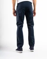 Pantalón de gabardina color beige, de corte recto, con bolsillos laterales y traseros. Se ajusta a la cintura con cinturón de cuero marrón.