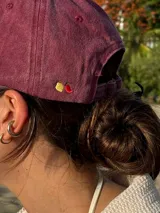 Gorra de béisbol color marrón con bordado frontal de la palabra "MILO" en color dorado.