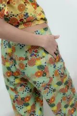 Pantalón largo verde agua con estampado de flores y piñas, corte recto con frunce en el tobillo.