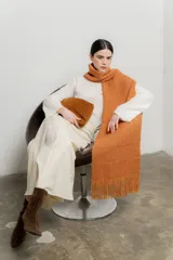 Bufanda larga tejida color ocre con flecos en los extremos.