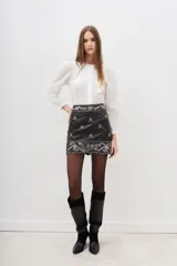 Minifalda negra de cuero ovino con apliques de lentejuelas y bordados plateados en la cintura y el ruedo.