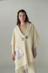 Chal de lana fina sin teñir, con calce en hombros, abrochadura con alamar de fieltro, bolsillos de cuero y terminación con flecos. Diseño exclusivo de Don Baez, hecho en Uruguay.