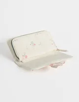 Billetera de cuerina color crema con estampado de flores y cierre con broche a presión.