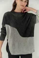 Buzo de punto con diseño geométrico en bloques de color gris y negro, de cuello redondo y mangas largas.