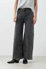 Pantalón de jean gris oscuro, corte wide leg, con tachas plateadas en los laterales.