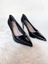 Zapato de tacón alto Iara, color negro charol, con punta fina y suela roja. Fabricado en cuero.