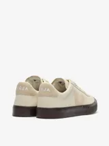 Zapatillas de cuero color blanco con detalles en beige claro, suela de goma marrón oscuro y cordones blancos.