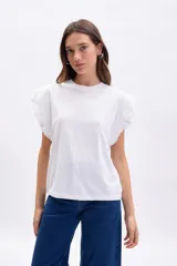 Remera de manga corta color blanco, con detalle de volados en broderie en las mangas y cuello redondo.