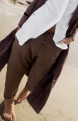 Pantalón de tiro bajo y calce relajado, color marrón oscuro, con cierre frontal de botones visibles. El largo es hasta el tobillo.