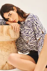 Sweater de tejido animal print con base color crema y rayas color azul y marrón. Tiene tajos laterales y lentejuelas bordadas.