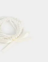 Set de cinco pulseras elásticas de perlas blancas con cinta de raso color crema.