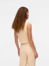 Chaleco color crema con bordado inglés, cierre frontal con botones y bolsillos tipo ojal.