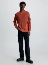 Sweater de punto texturizado color ladrillo, con cuello redondo, mangas largas raglán y logo de Calvin Klein en la manga.