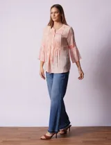 Blusa de gasa estampada color salmón con flores blancas, marca Ruby Rd. Cuello a la base, escote en V y abertura central con botones. Delantera con plisados. Largo de manga ¾ con terminación amplia.