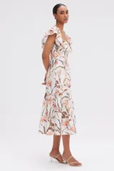 Vestido midi blanco con estampado floral en tonos naranja y marrón. Presenta escote cuadrado con volados, mangas cortas con volados y falda escalonada con volados.