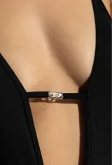 Traje de baño entero negro de corte alto, con tirantes finos, escote en V profundo y dije metálico con el logo de la marca en el centro del busto.