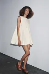 Vestido corto color crema con escote en V y sisas anchas. Tiene forro interior combinado a tono.