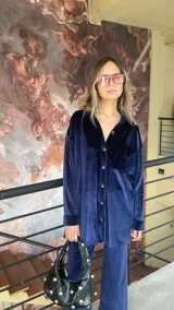 Camisa azul de terciopelo, corte oversize, con cuello camisero, manga larga y cierre frontal con botones.
