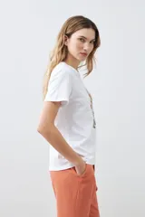 Remera blanca de algodón con cuello redondo y mangas cortas. Estampa frontal con bordado de flores y frase 'Just keep flowing'.