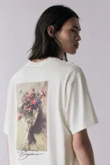 Remera blanca de corte holgado con estampado de texto en cursiva color negro en el centro del pecho.