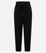 Pantalón fluido de cintura alta, confeccionado en crepé, con elástico y lazo en la cintura. Presenta un estampado geométrico con líneas curvas horizontales.