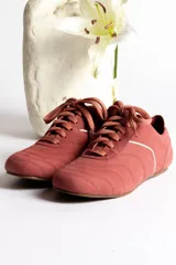 Zapatillas deportivas color ladrillo con cordones y detalles en blanco.
