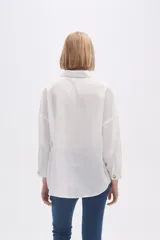 Blusa blanca holgada de poliéster con cuello camisero y mangas largas.