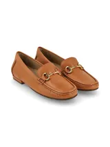Mocasín de cuero color crema con detalle de hebilla metálica plateada.