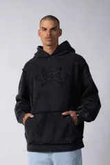 Buzo canguro negro con capucha, calce oversize, confeccionado en frisa 100% algodón con lavado gastado y aplique cosido en el pecho.