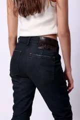 Pantalón de jean de tiro medio, color azul oscuro, con efecto lavado y arrugas en la parte inferior de las piernas.