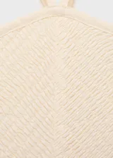 Vestido midi color crudo, con escote halter y tirantes finos. El corpiño es ajustado y texturizado, mientras que la falda es amplia y fluida.