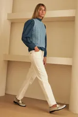 Chaleco marrón de punto con diseño trenzado, cuello redondo y sisas con volantes celestes.