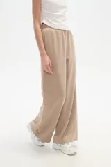 Pantalón deportivo negro de corte holgado, con cintura elástica, bolsillos laterales y botones a presión en las costuras laterales de las piernas.