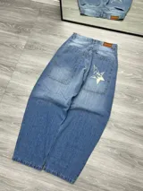 Pantalón de jean celeste de corte amplio con bolsillos laterales y traseros. Presenta un estampado de una estrella blanca en el bolsillo trasero derecho.