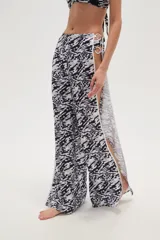 Pantalón largo de tela fluida con estampado de cebra en tonos rosa y fucsia. Tiene corte ancho y aberturas laterales con detalle de argollas.