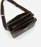 Cartera transversal de material sintético color marrón oscuro, de forma rectangular y estructura rígida. Presenta pespuntes decorativos en color blanco en los bordes frontales y cierres metálicos dorados. Incluye un asa ancha desmontable con diseño de rayas beige y marrón.