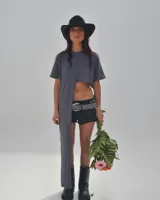 Short de jean negro con terminaciones desflecadas y cinturón de cuero negro con argollas plateadas.