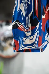 Calza corta deportiva con tiro alto y estampado abstracto en tonos rojo, azul, blanco y negro.