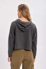 Canguro deportivo cropped gris oscuro con capucha y cordones ajustables. Corte holgado y mangas largas con puños ajustados.