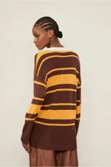 Top de punto de manga larga con cuello polo blanco, escote en V profundo y rayas horizontales en tonos marrón y mostaza. Los puños y el bajo son acanalados.