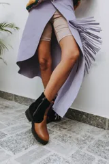 Botas cortas de cuero color caramelo con caña superior de material negro texturizado (tipo corderito o borrego). Cierre lateral con cremallera plateada y suela gruesa de goma negra con relieve.