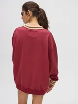 Buzo blanco de corte redondo (crew neck) con puños ajustados que tienen rayas rojas y blancas. Presenta un estampado central de un velero navegando con texto alrededor.