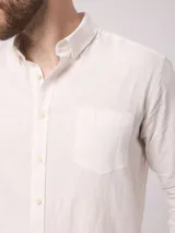 Camisa de manga larga azul, de lino y poliéster, con cuello abotonado y bolsillo en el pecho.