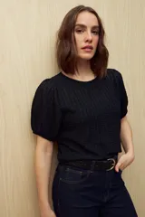 Top negro de tejido texturizado con mangas cortas abullonadas y cuello redondo.