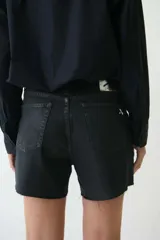 Short de jean negro con tachas plateadas y terminación desflecada.